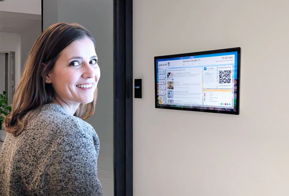 Frau schaut auf Digitale Haustafel im Hauseingang